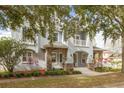 Two story house, light gray, stone accents, mature trees, manicured lawn at 3366 Cat Brier Trl, Harmony, FL 34773