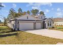 Two-story house with gray and white exterior, three-car garage, and landscaping at 10560 Sw 49Th Avenue Rd, Ocala, FL 34476