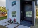 Modern house entrance with dark gray siding, white trim, and red plants at 716 W 14Th St, Lakeland, FL 33805