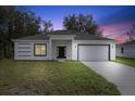 Modern single story home with white exterior, gray roof, and a black front door at dusk at 1312 Congo Dr, Poinciana, FL 34759