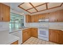 Kitchen with wood cabinets, white appliances, and tiled floor at 7491 Limonia Dr, Indian Lake Estates, FL 33855