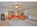 Bright living room featuring orange sofas, coffee table, and carpet at 7491 Limonia Dr, Indian Lake Estates, FL 33855