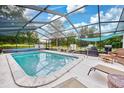 Relaxing screened pool area with patio furniture and grilling station at 7491 Limonia Dr, Indian Lake Estates, FL 33855