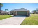 Single-story house featuring a green garage door and spacious yard at 930 Chelsea Way, Lake Wales, FL 33853