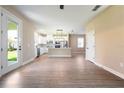 Open-concept kitchen and dining area with white cabinets, stainless steel appliances, and wood-look flooring at 7837 Somersworth Dr, Kissimmee, FL 34747