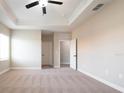Spacious main bedroom with plush carpeting, a ceiling fan, and tray ceiling at 7837 Somersworth Dr, Kissimmee, FL 34747