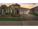 Inviting single-story home at sunset with a stone and stucco facade, paver driveway, and lush landscaping at 1767 Bee Nice Dr, Kissimmee, FL 34744