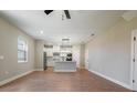 Open-concept living area with wood-look flooring, a ceiling fan, and views into the kitchen at 7853 Somersworth Dr, Kissimmee, FL 34747