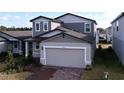 Two-story house with gray siding, a two-car garage, and a brick driveway at 4936 Mainsail Street, Haines City, FL 33844