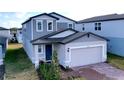 Two-story house with gray siding, brick driveway, and a two-car garage at 4936 Mainsail Street, Haines City, FL 33844