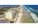 Aerial view of beachfront property with ocean, pier, and building at 3743 S Atlantic Ave # 3D00, Daytona Beach Shores, FL 32118