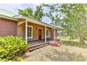 Brick house with a front porch, red door, and green roof at 1430 Hazen Rd, Deland, FL 32720