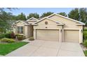 Tan two-story house with two-car garage, lush landscaping, and a manicured lawn at 509 W Victoria Trails Blvd, Deland, FL 32724
