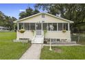 Charming yellow house with a screened porch and landscaped lawn at 409 W Beresford Ave, Deland, FL 32720