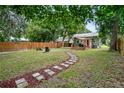 Landscaped backyard with stone path leading to a deck and wooden chairs at 112 S Chandler Ave, Deland, FL 32724