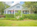 A light blue house with white trim, a porch, and lush landscaping at 450 W Delaware Ave, Lake Helen, FL 32744