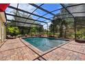 Inviting pool area with screened enclosure, brick pavers, and lush landscaping at 1440 Deerfoot Rd, Deland, FL 32720