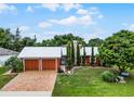 Red home with metal roof, two-car garage, and landscaped yard at 980 Bluebird Ter, Deltona, FL 32725