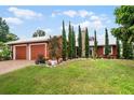 Red two-car garage home with brick driveway and landscaped yard at 980 Bluebird Ter, Deltona, FL 32725