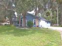 Blue house exterior with stone accents, spacious yard, and mature trees at 573 Pelican Bay Dr, Daytona Beach, FL 32119