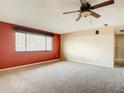 Spacious bedroom with red accent wall, ceiling fan, and carpeted floor at 3642 Socha Way, Port Orange, FL 32129