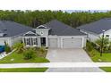 Gray three-car garage home with landscaping and paver driveway at 397 Aquamarine Way, Daytona Beach, FL 32124