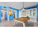Beachy dining area with a wooden table, white china cabinet, and blue walls at 1415 Ocean Shore Blvd # 303, Ormond Beach, FL 32176