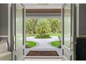 View through front doors showcasing a circular driveway and lush landscaping at 4 Broad Creek Cir, Ormond Beach, FL 32174