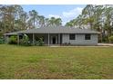 Gray house with covered porch, stone accents, and a lush green lawn at 2390 Meadow Ln, Port Orange, FL 32128