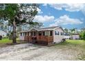 Tan one-story house with a wooden porch and large tree in the front at 1230 8Th Ave, Deland, FL 32724