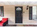 Black front door with a red chair on the porch at 1230 8Th Ave, Deland, FL 32724