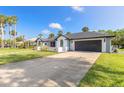 Front view of a modern home with a driveway and green lawn at 6178 Knotty Pine Ct, Port Orange, FL 32127
