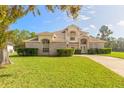 Two-story brick home with a large front yard, driveway, and mature landscaping at 6180 Knotty Pine Ct, Port Orange, FL 32127
