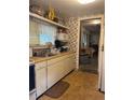 Small kitchen with light cabinets, floral wallpaper, and vintage appliances at 969 Lemon Bluff Rd, Osteen, FL 32764