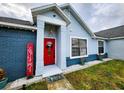 Red front door entryway, flanked by blue painted walls and landscaping at 1831 Trumbull St, Deltona, FL 32725