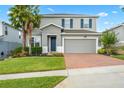 Two-story house with gray siding, brick driveway, and palm trees at 3404 Grassy Lake View Ave, Minneola, FL 34715