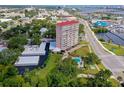 High-angle aerial view of The Landmark building with a pool, parking, and surrounding trees at 404 S Beach St # 010 101, Daytona Beach, FL 32114