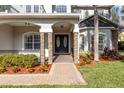 Elegant entryway with double doors, stone columns, and a paved walkway at 973 Bearded Oaks Ter, Longwood, FL 32779