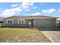 Gray house with a grassy yard, attached garage, and a driveway at 326 Oak Track Loop, Ocala, FL 34472