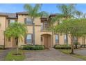 Front view of townhome with palm trees and brick driveway at 216 Calabria Ave, Davenport, FL 33897
