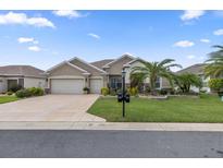 Tan two-car garage home with lush landscaping at 13532 Se 89Th Terrace Rd, Summerfield, FL 34491