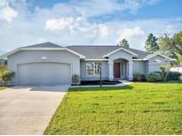 Single-story home with a two-car garage, and a well-manicured lawn at 518 Marion Oaks Trl, Ocala, FL 34473