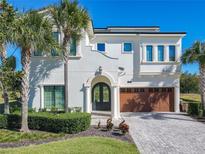 Two-story house with stucco siding, arched entry, and a three-car garage at 550 Muirfield Loop, Reunion, FL 34747