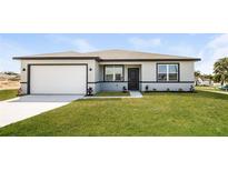 Modern one-story home with gray and white exterior and two-car garage at 802 Fraser Dr, Poinciana, FL 34759