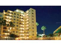 Night view of a multi-story building with pool and lush landscaping at 6165 Carrier Dr # 1105, Orlando, FL 32819