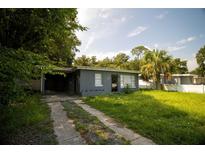 Gray house with carport and overgrown lawn at 809 Maley St, Daytona Beach, FL 32114