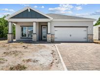 One-story home with gray siding, stone accents, and a two-car garage at 1250 Champions Dr, Daytona Beach, FL 32124