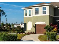 Two-story house with brown garage door and landscaping at 241 Tarracina Way, Daytona Beach, FL 32117