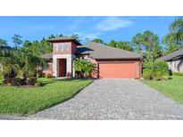 Beautiful two-story house with a reddish exterior, paver driveway and landscaping at 660 Aldenham Ln, Ormond Beach, FL 32174