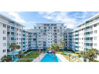 View of beachfront condominium building with a pool and lush landscaping at 2727 N Atlantic Ave # 203, Daytona Beach, FL 32118
